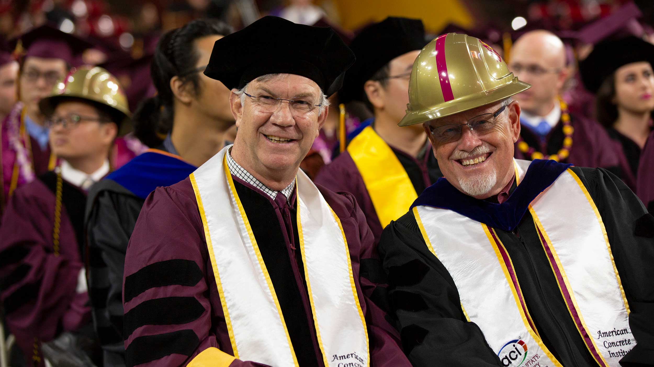 Richard Standage and Jim Ernzen smile for the camera at Convocation, dressed in their full regalia