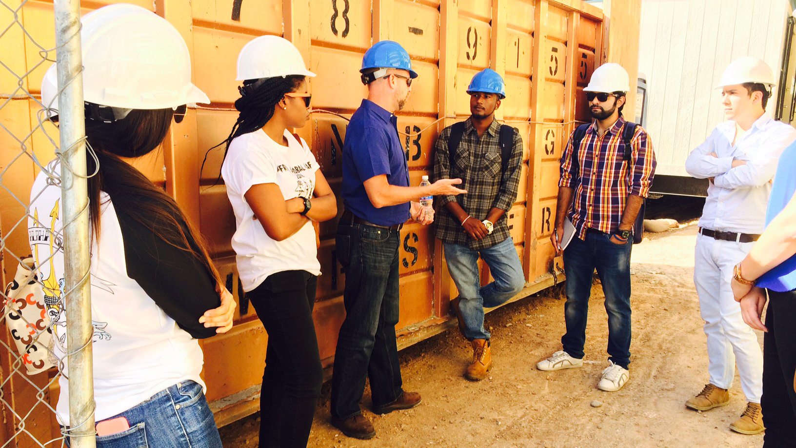 A group of students listens to an industry professional at a construction site