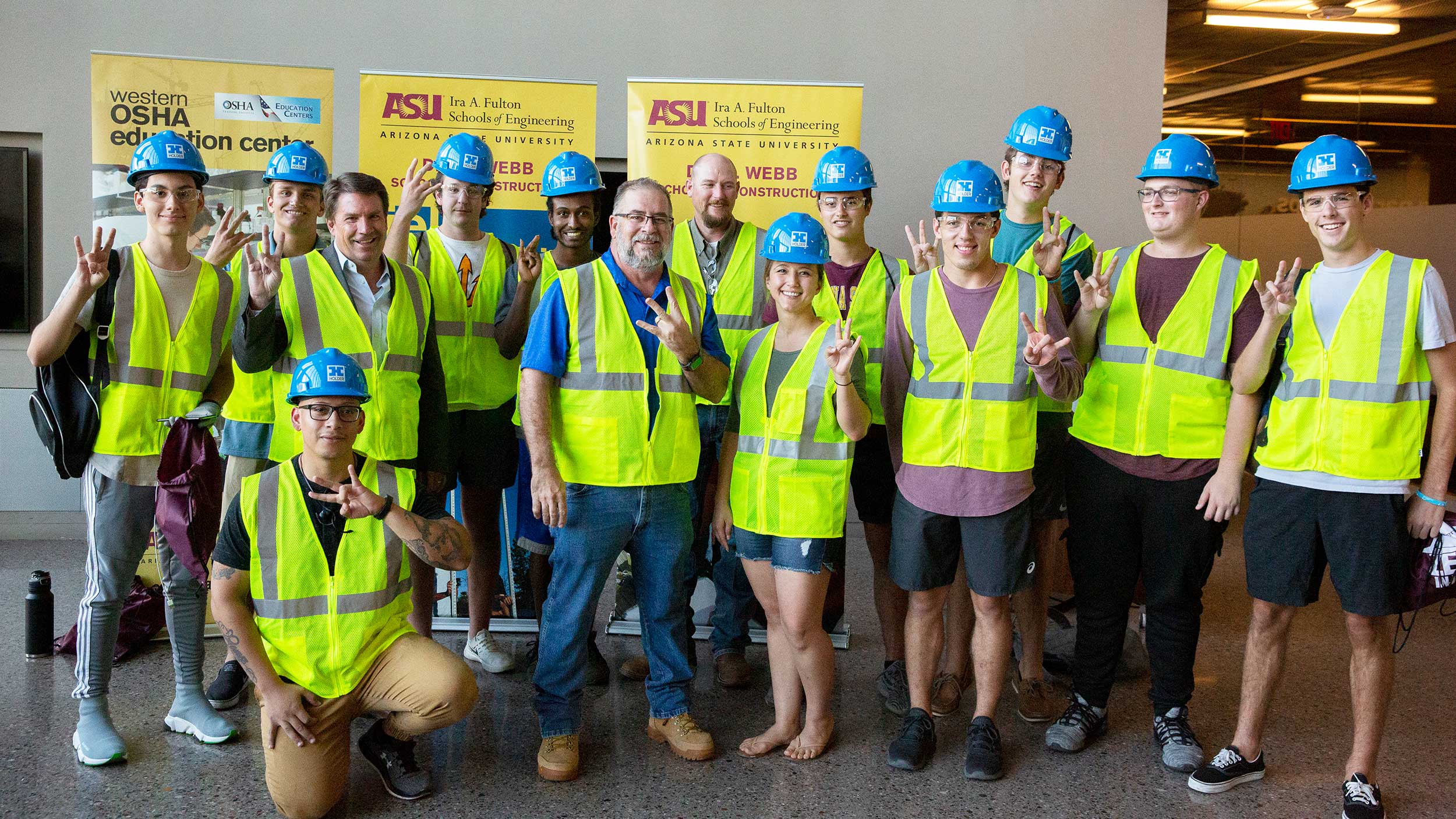 A group of newly "vested" construction freshmen stand for a group photo with faculty and industry professionals