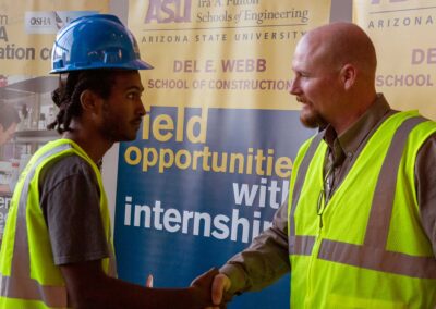 An industry professional shakes hands with a DEWSC student at the vesting ceremony during Safety Week