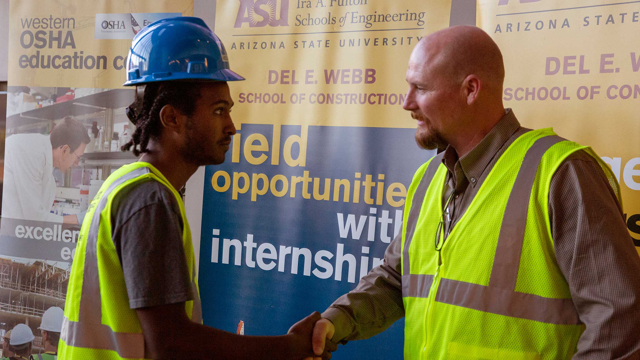 An industry professional shakes hands with a DEWSC student at the vesting ceremony during Safety Week